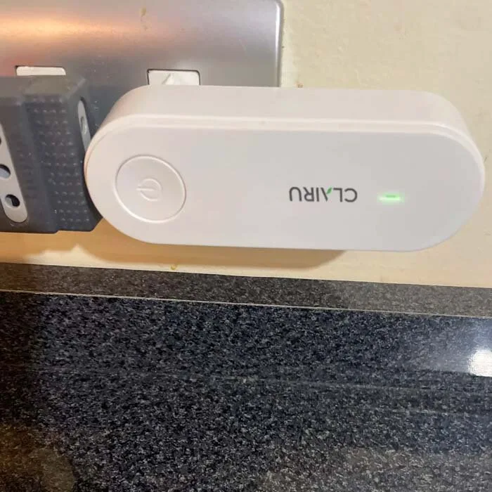Clairu plug-in air purifier plugged into a wall socket above a kitchen counter