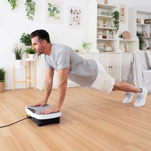 Man doing a plank with hands on the Herz P1 vibration plate in a living room
