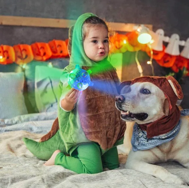 Child in a dinosaur costume with a dog and a glowing dog ball