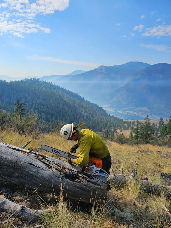Firefighter sharpening a chainsaw chain during maintenance