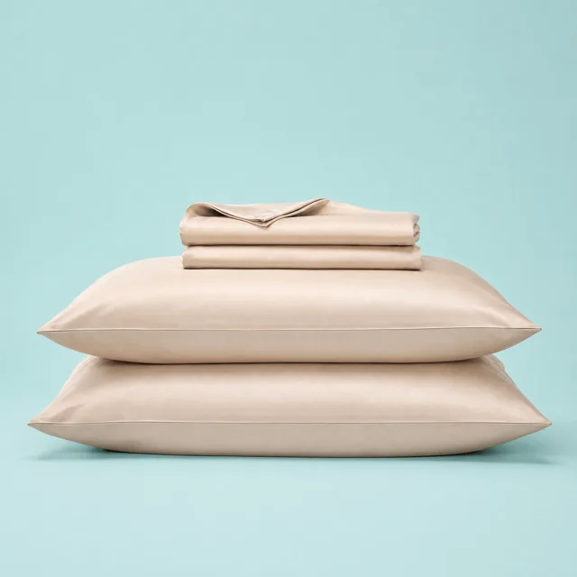 The Sleepgram bamboo sheet set in the warm Sand color, neatly folded showing the sateen weave